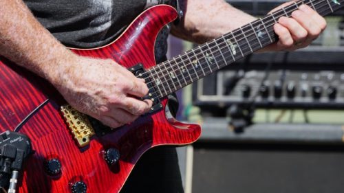 Man playing red electric guitar. Electric guitars are fun and easy for beginners.