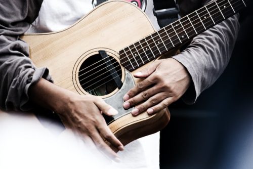 Man holding an acoustic guitar. Acoustic guitars are a great choice for beginners.