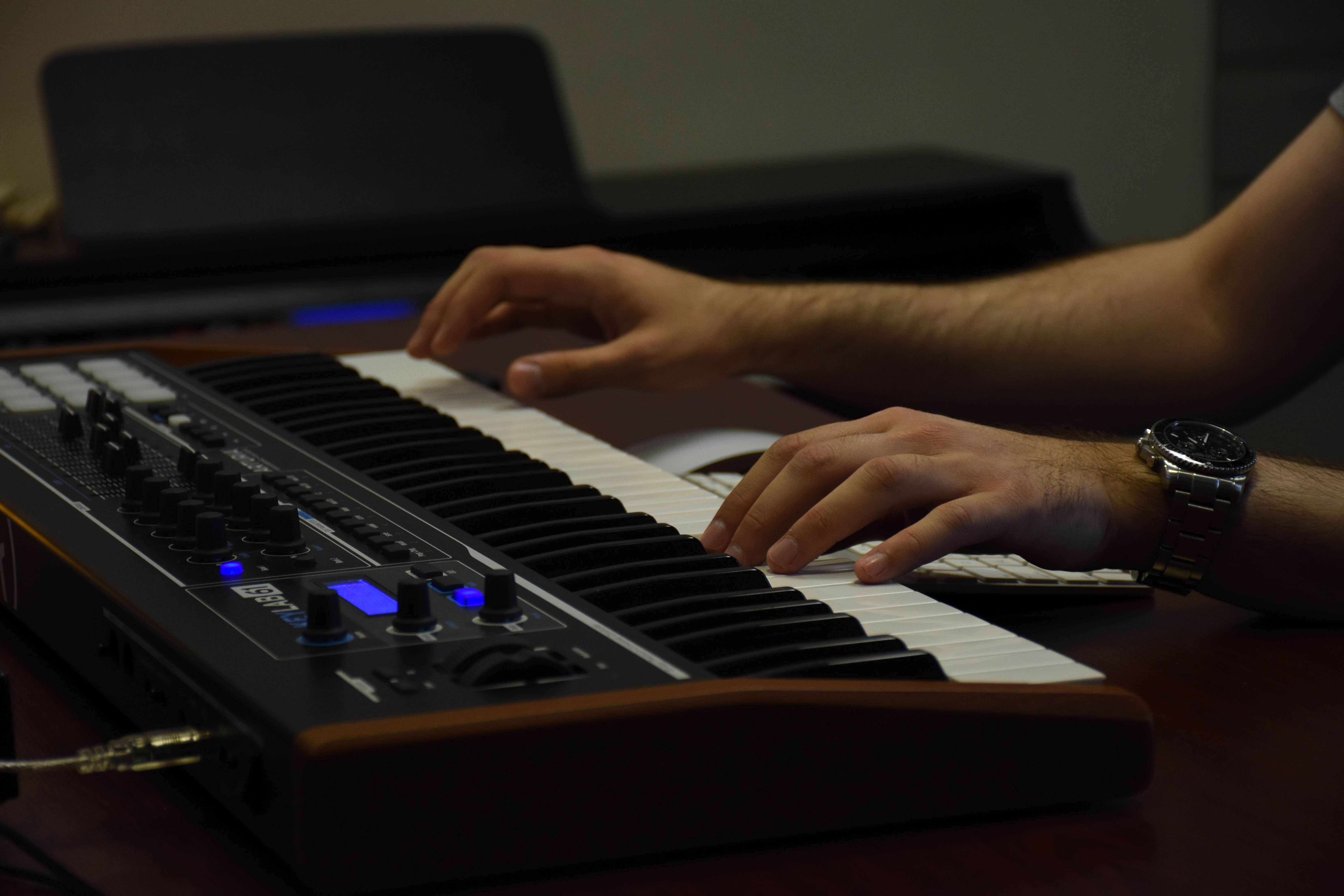 A man's hands play on a MIDI controller.